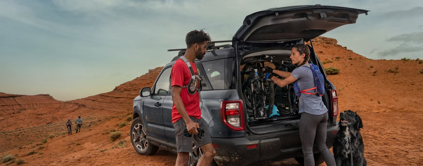 Two people getting equipment out of the trunk of a blue 2026 Ford Bronco Sport