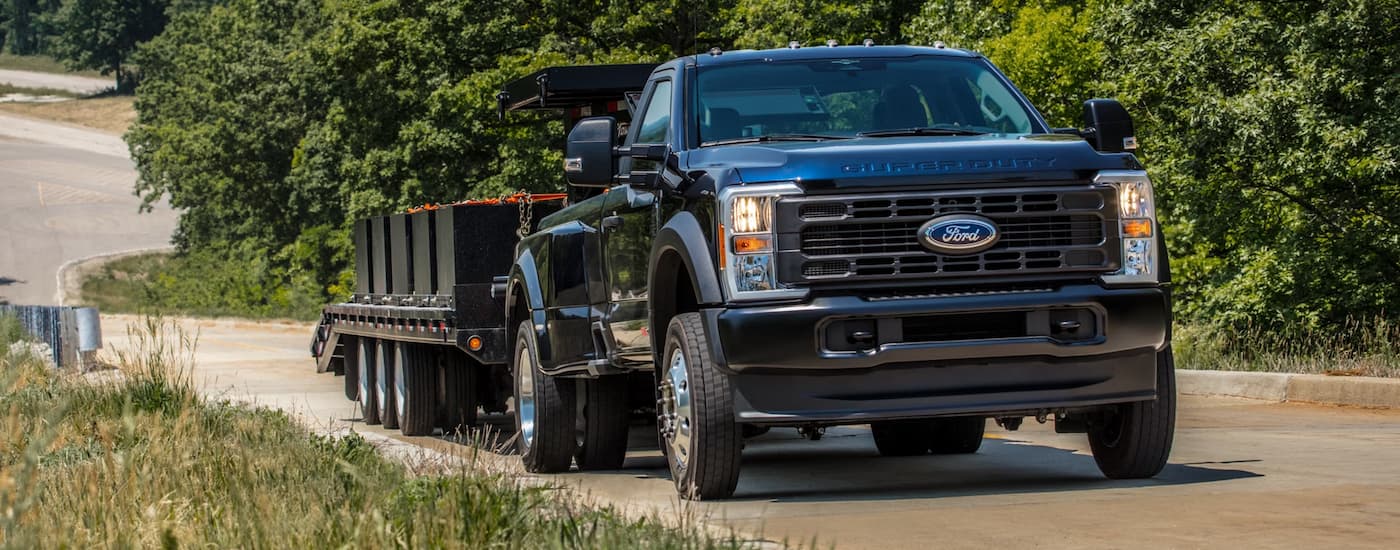 Black 2026 Ford F-350 towing a trailer down a dirt road.