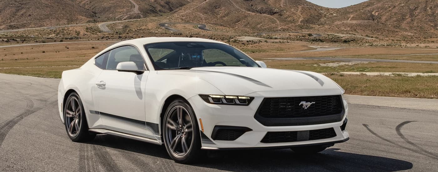 White 2026 Ford Mustang driving down a road.