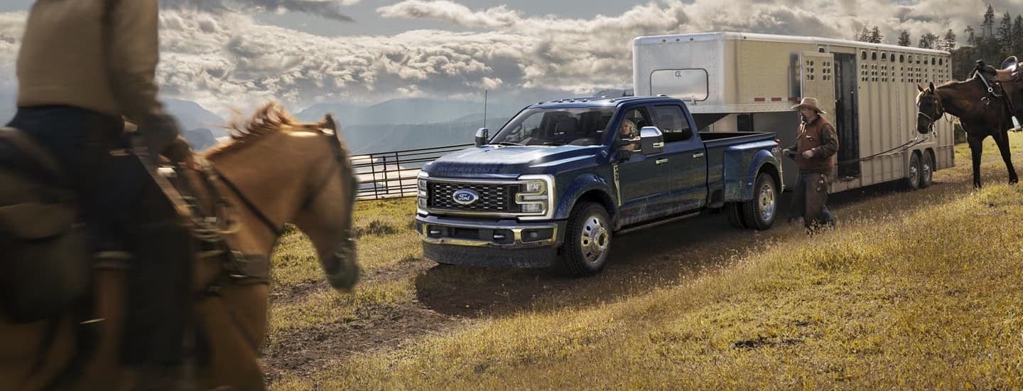 A dark blue 2025 Ford F-450 towing a trailer down a hill after visiting a dealer with a Ford Super Duty for sale near Franklin.