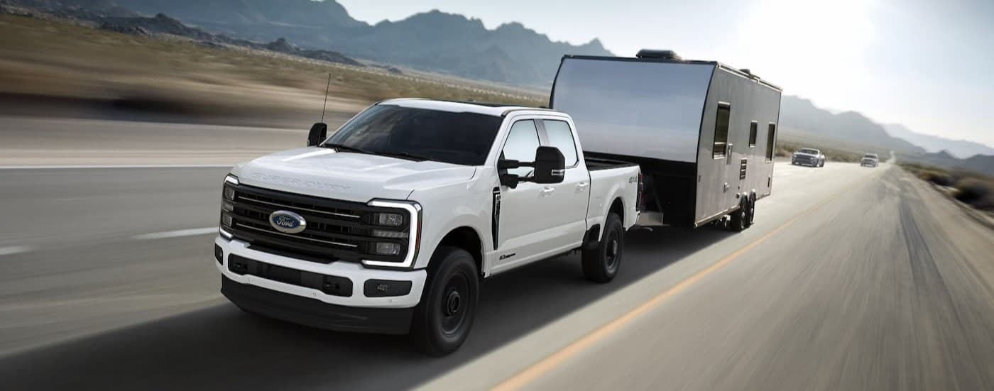 A white 2025 Ford F-350 Super Duty towing a trailer.