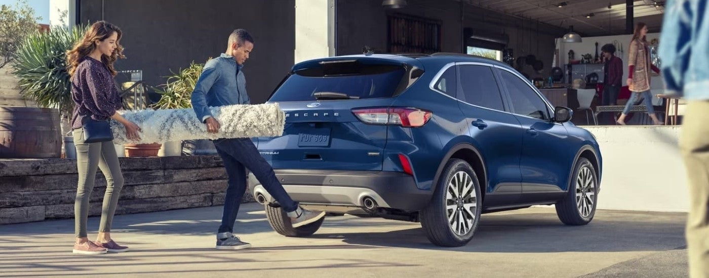 People are shown loading a rug into a blue 2022 Ford Escape Titanium.