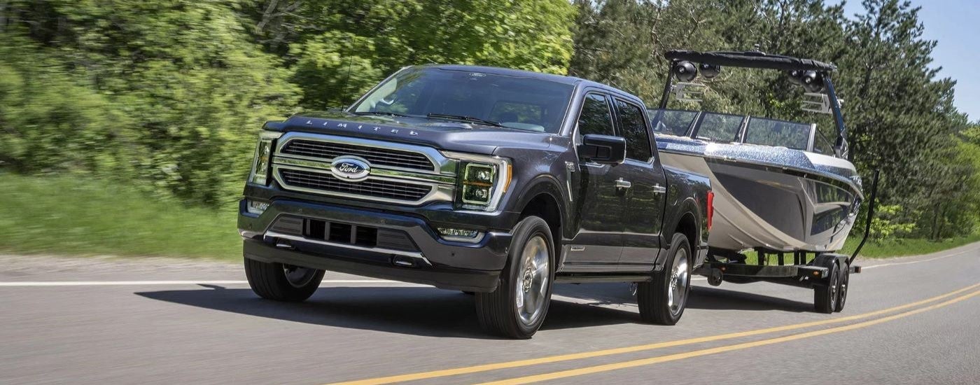 A black 2023 Ford F-150 Limited is shown driving to a used car dealer.