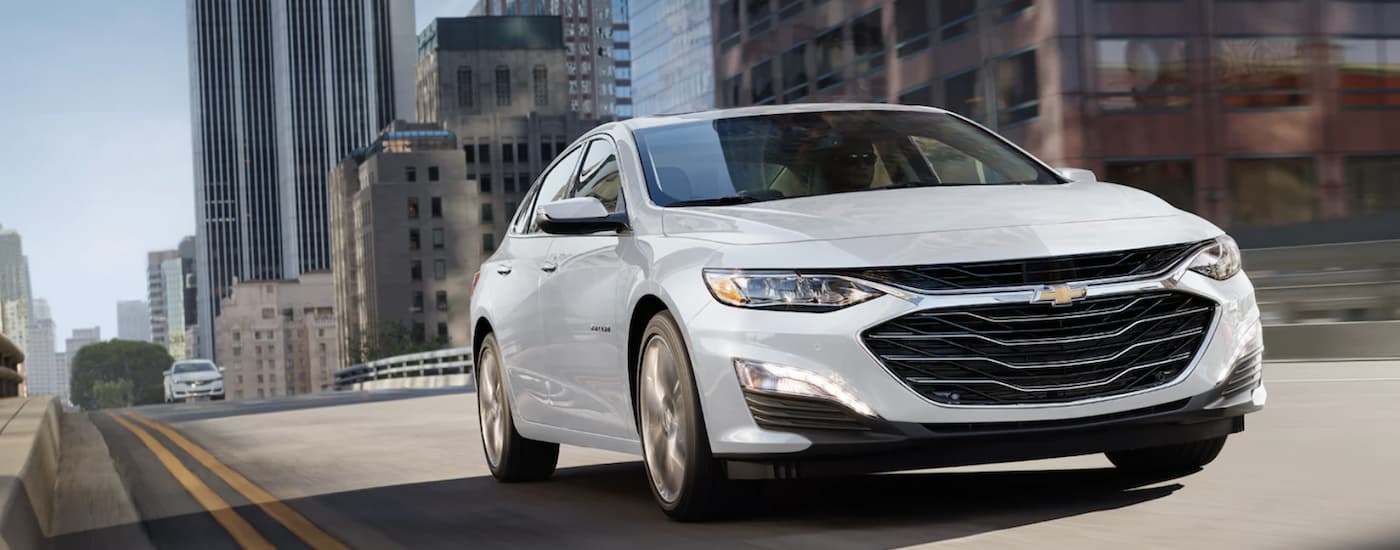 White 2022 Chevy Malibu driving across a bridge.